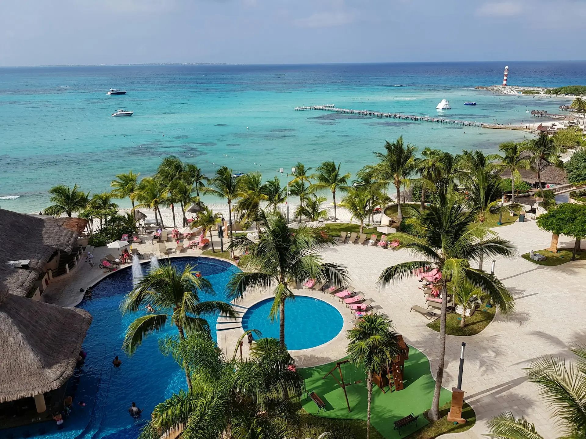 Vista desde un Resort con Palmeras, piscina y una playa de fondo